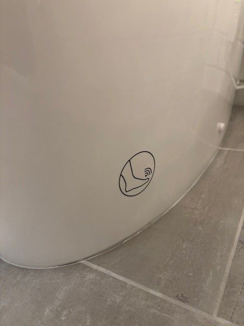 A close up of a toilet with a sticker on it.