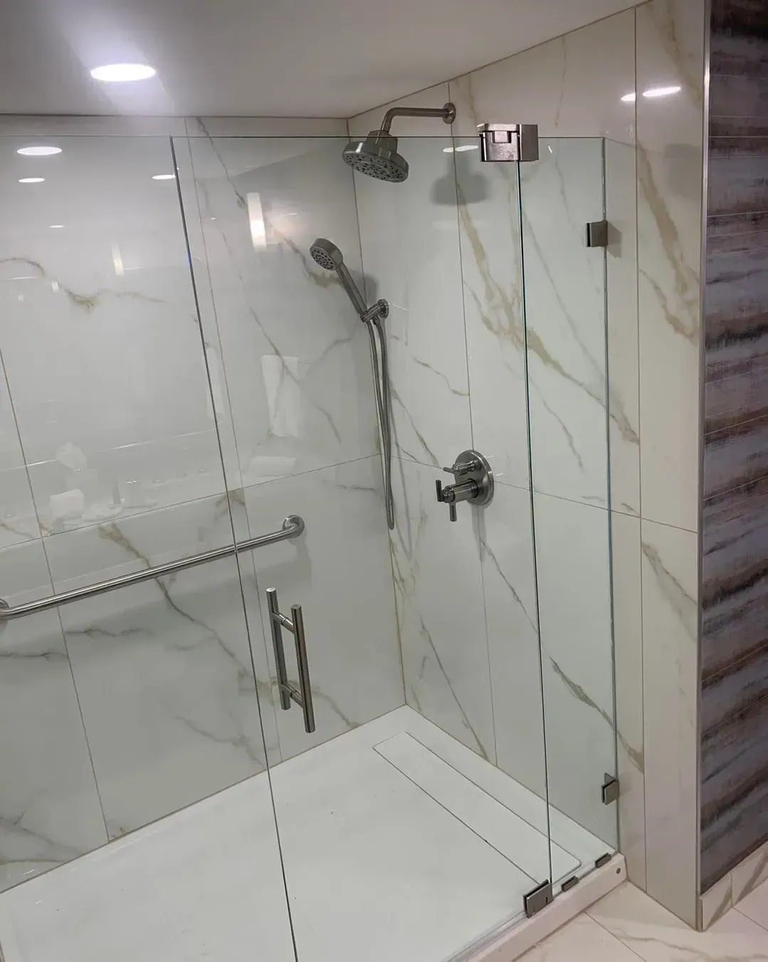 A bathroom with a walk in shower with a glass door.