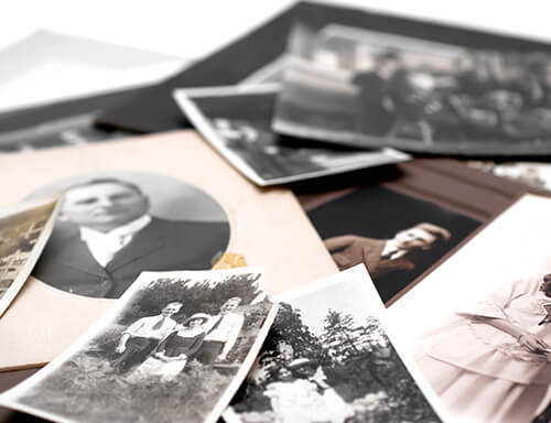 A pile of old photographs including a man in a suit and a woman in a pink dress