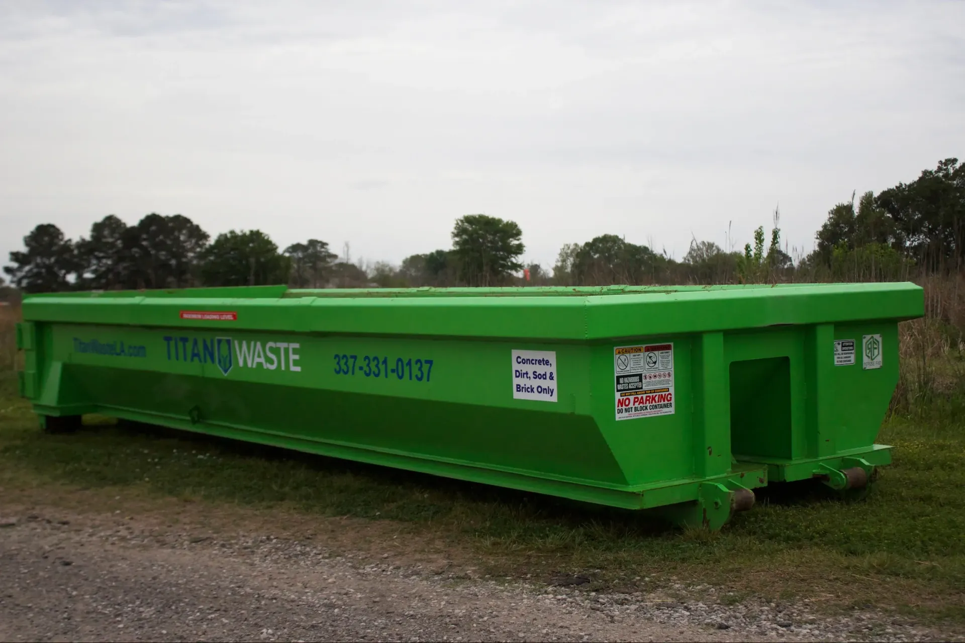 A green dumpster is parked on the side of the road.