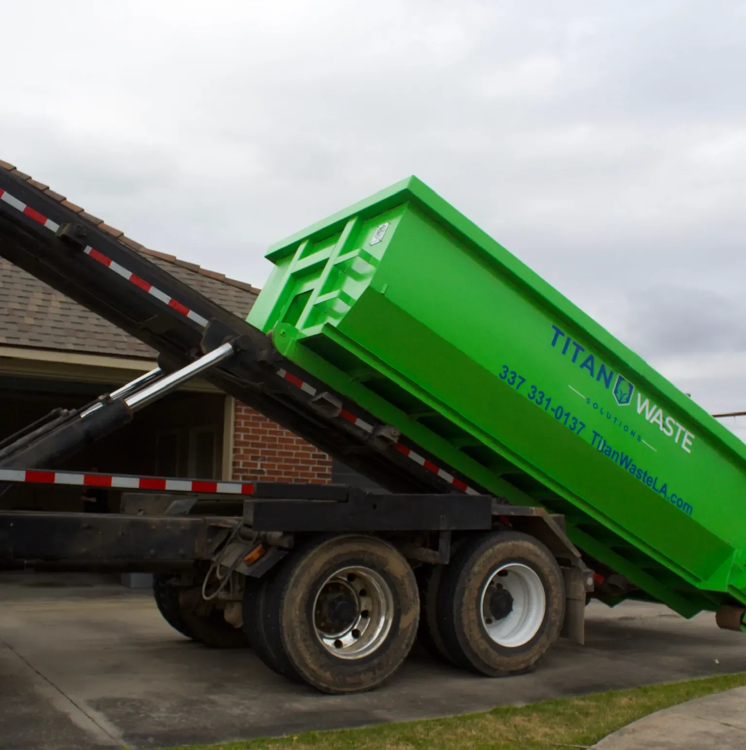 A green titans waste dumpster on a trailer