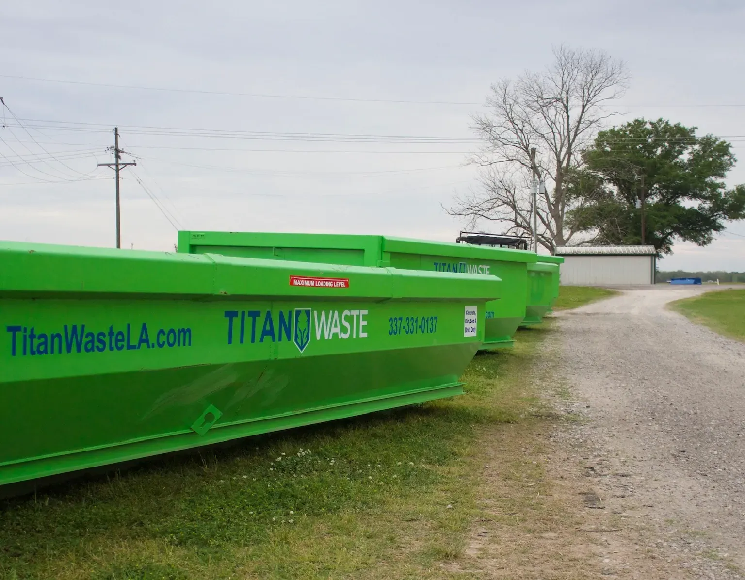 A row of green dumpsters with titanwastela.com written on them