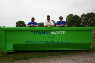 Three men are standing next to a green dumpster.
