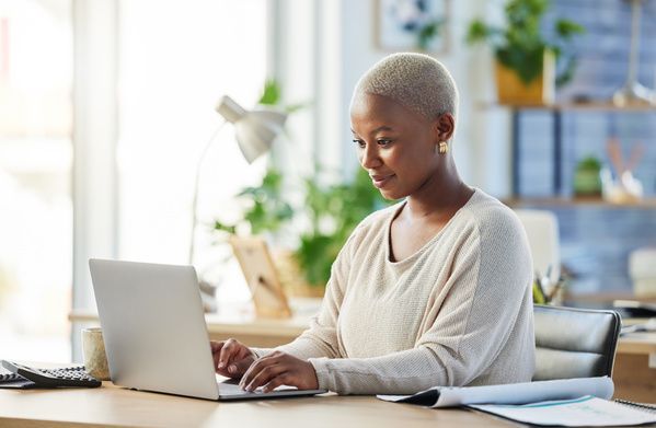 Person working on a laptop at a desk in a bright home office