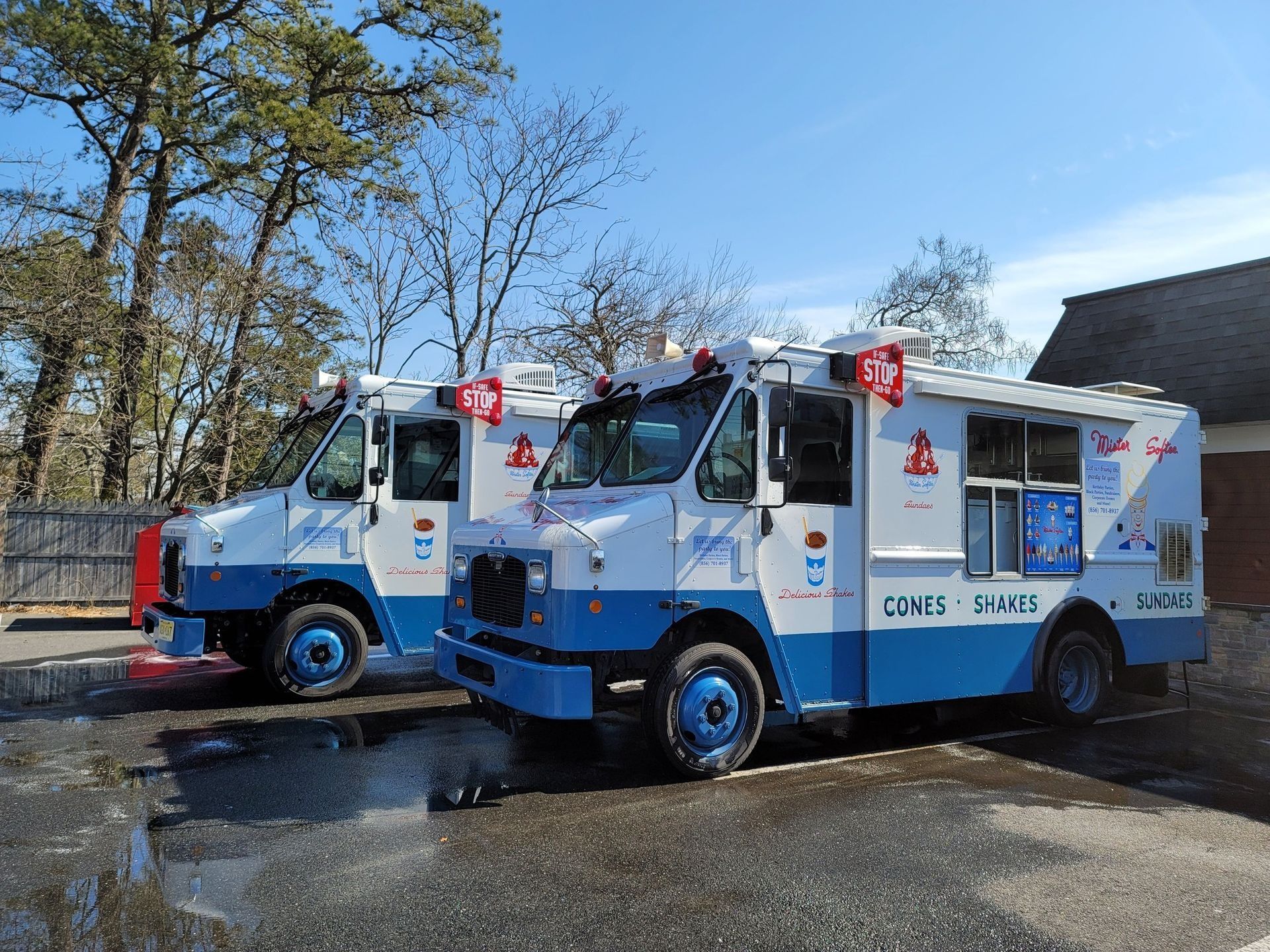 Two people holding a large poster beside a road in a grassy field on a sunny day