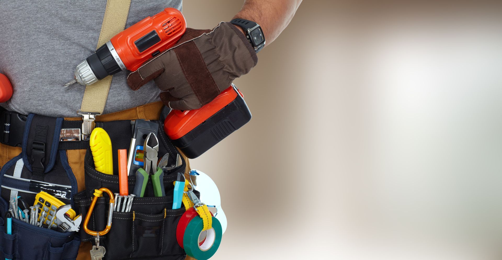 Technician holding a red heat gun over a tool belt full of pliers, screwdrivers, and other tools