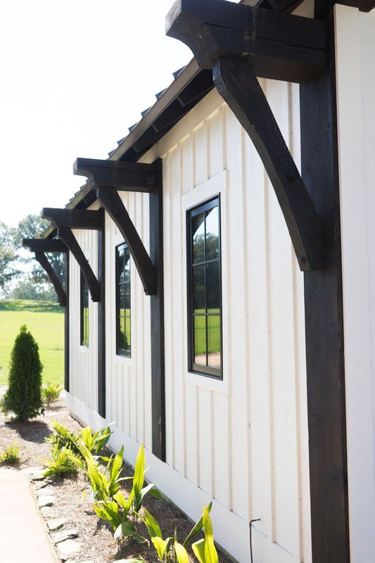 White house exterior with dark timber trim, windows, and a small landscaped garden along the wall