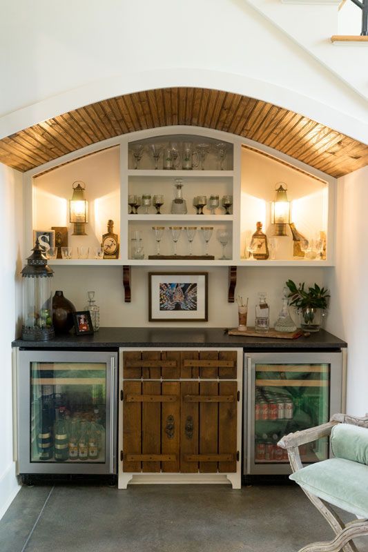 Built-in bar nook with wood arches, shelves, cabinets, and glass-front mini fridges in a cozy room