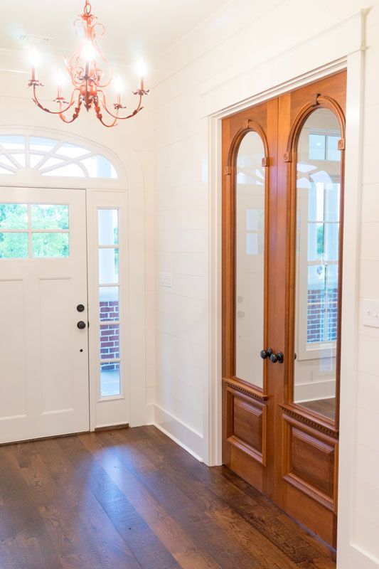 Bright foyer with white walls, hardwood floor, chandelier, front door, and wooden double closet doors