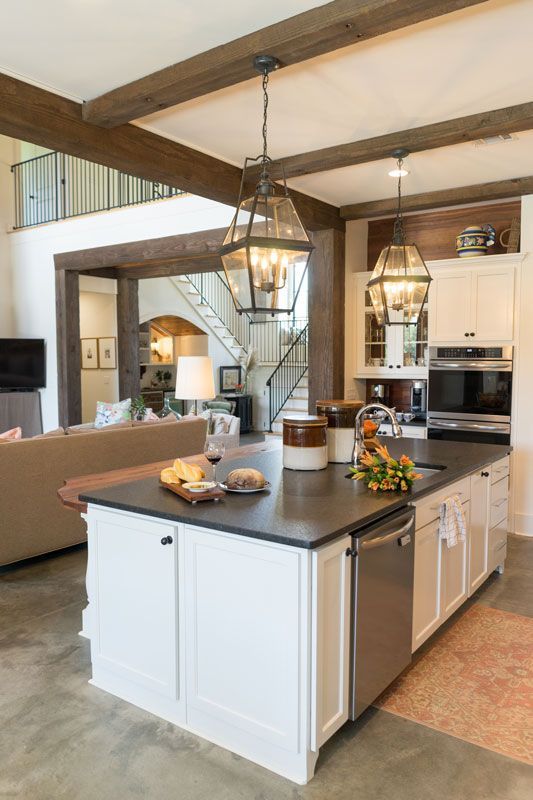 Modern kitchen with island, pendant lights, white cabinets, and exposed wooden beams