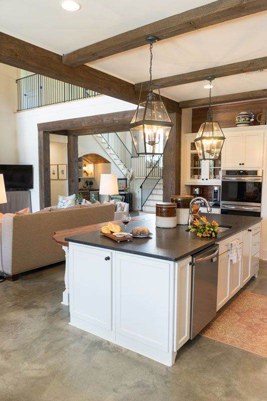 Modern kitchen with island, white cabinets, exposed beams, and pendant lights