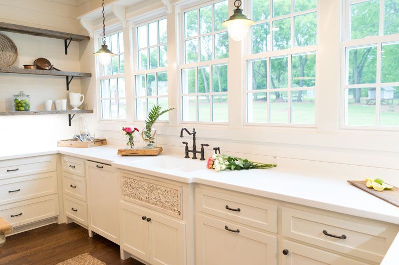 Bright white kitchen with large windows, marble countertops, and light wood cabinets