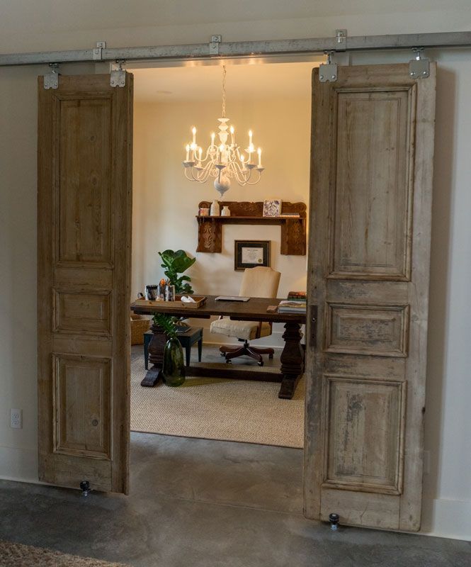 Open doorway with tall wooden shutters framing a dining room and chandelier beyond