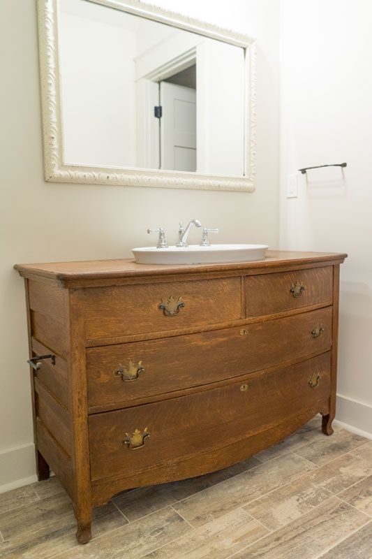 Vintage wooden dresser with sink and mirror in a bright bathroom