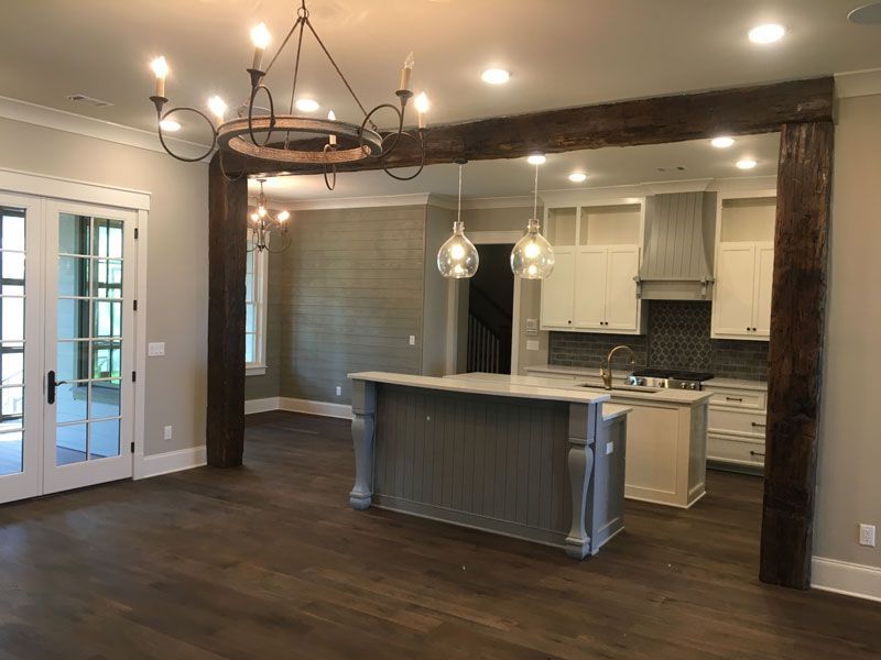 Open-plan kitchen and dining area with dark wood floors, white cabinets, island, and hanging pendant lights.
