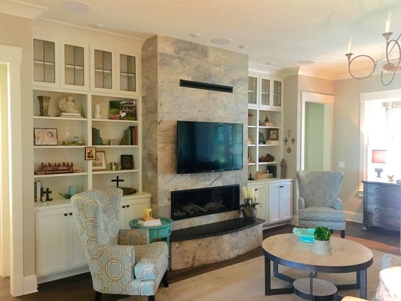 Bright living room with built-in shelves, wall-mounted TV, fireplace, and round coffee table