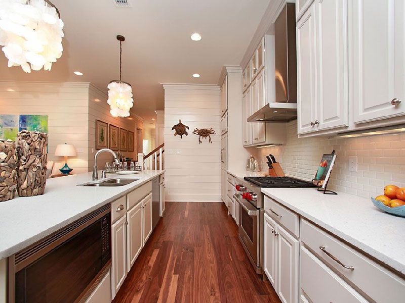 Bright modern kitchen with white cabinets, stainless appliances, and a long island with pendant lights.