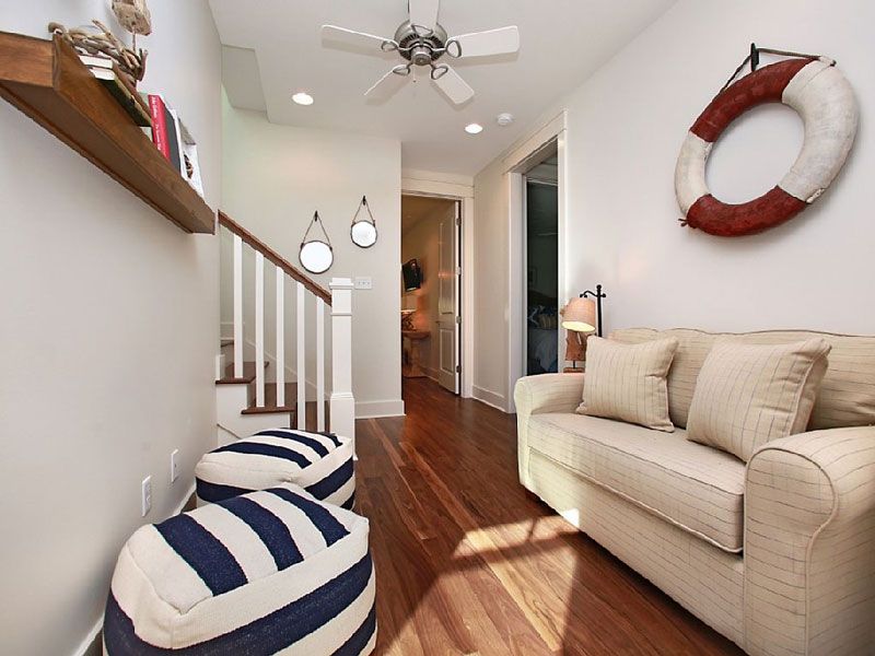 Cozy hallway with a beige sofa, navy-and-white pouf, striped runner, and a red-and-white wall wreath