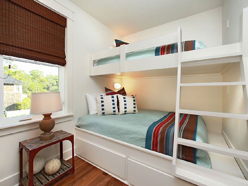 Bright bedroom with bunk bed, white walls, teal bedding, striped accents, and a window with a brown blind