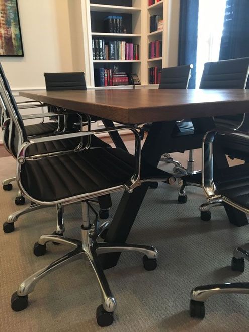 Conference room with black chairs around a wooden table and bookshelves in the background
