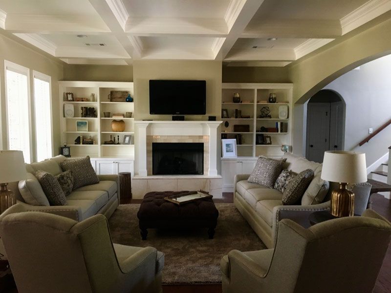 Elegant living room with beige sofas, fireplace, built-in shelves, and a wall-mounted TV