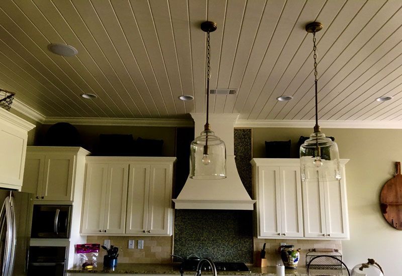 Kitchen with white cabinets, black tile backsplash, island lights, and a guitar on the right wall
