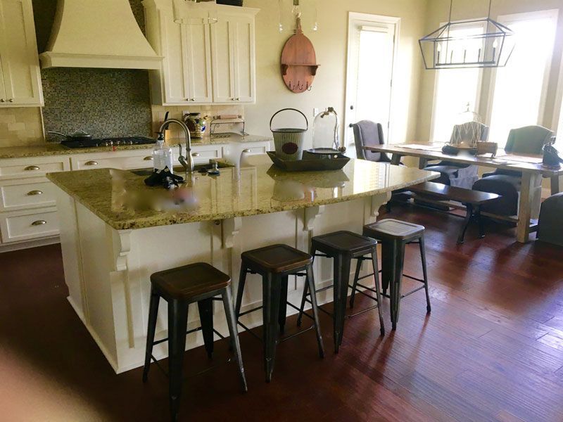 Bright kitchen with a large island, bar stools, and a dining table near the windows.