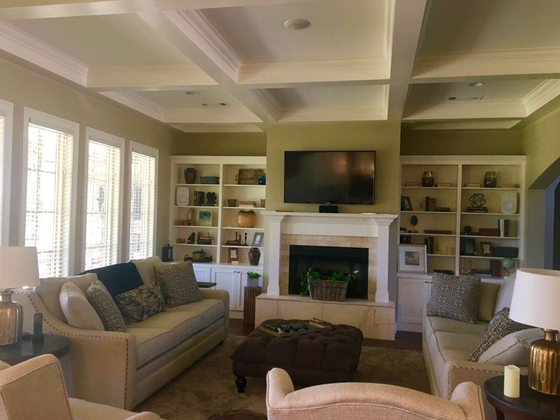 Elegant living room with beige sofas, built-in shelves, a fireplace, and a wall-mounted TV