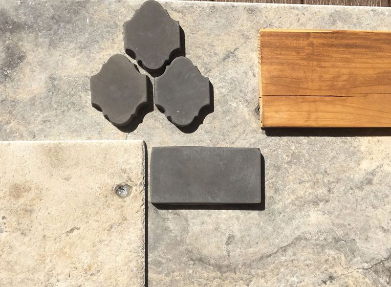 Three black pavers, a gray paver, and a wooden plank on a stone surface