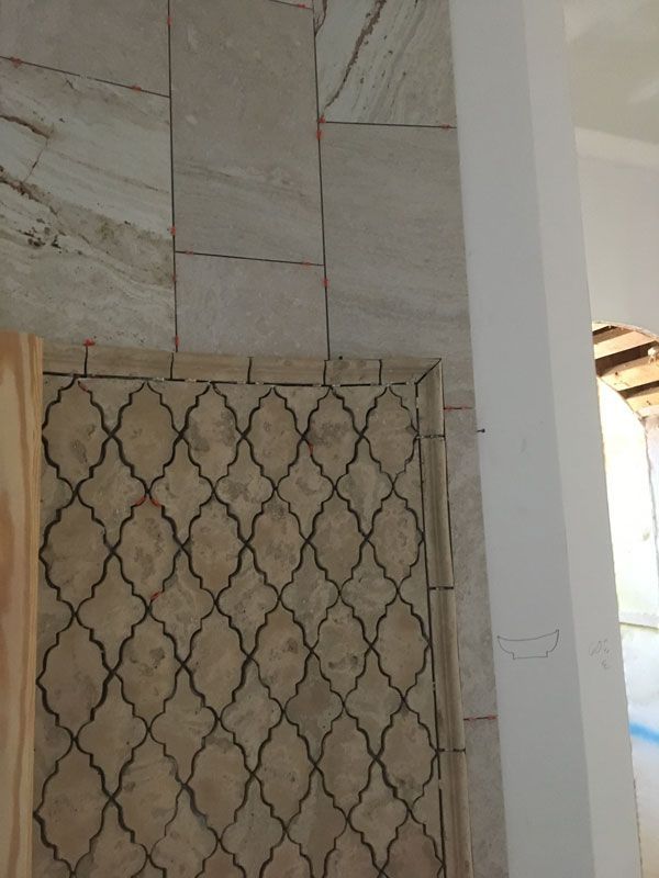 Tiled wall and decorative floor tiles beside a white doorway in a narrow interior space