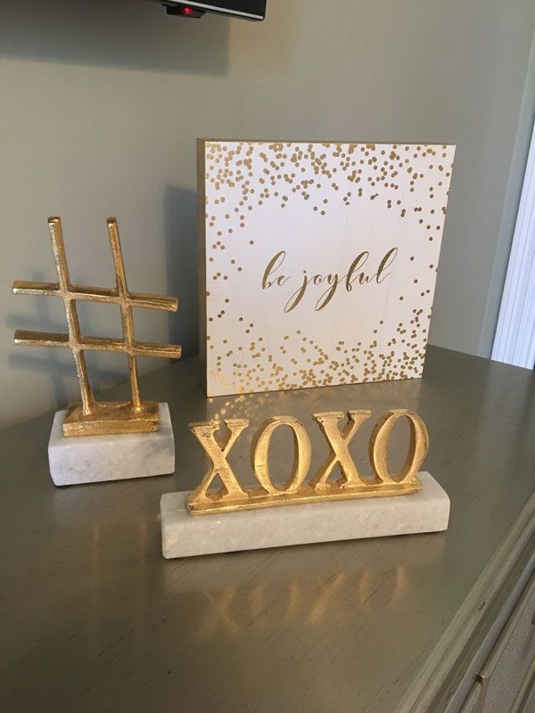 Gold decorative signs on a shelf with a white “Congrats!” card behind them.
