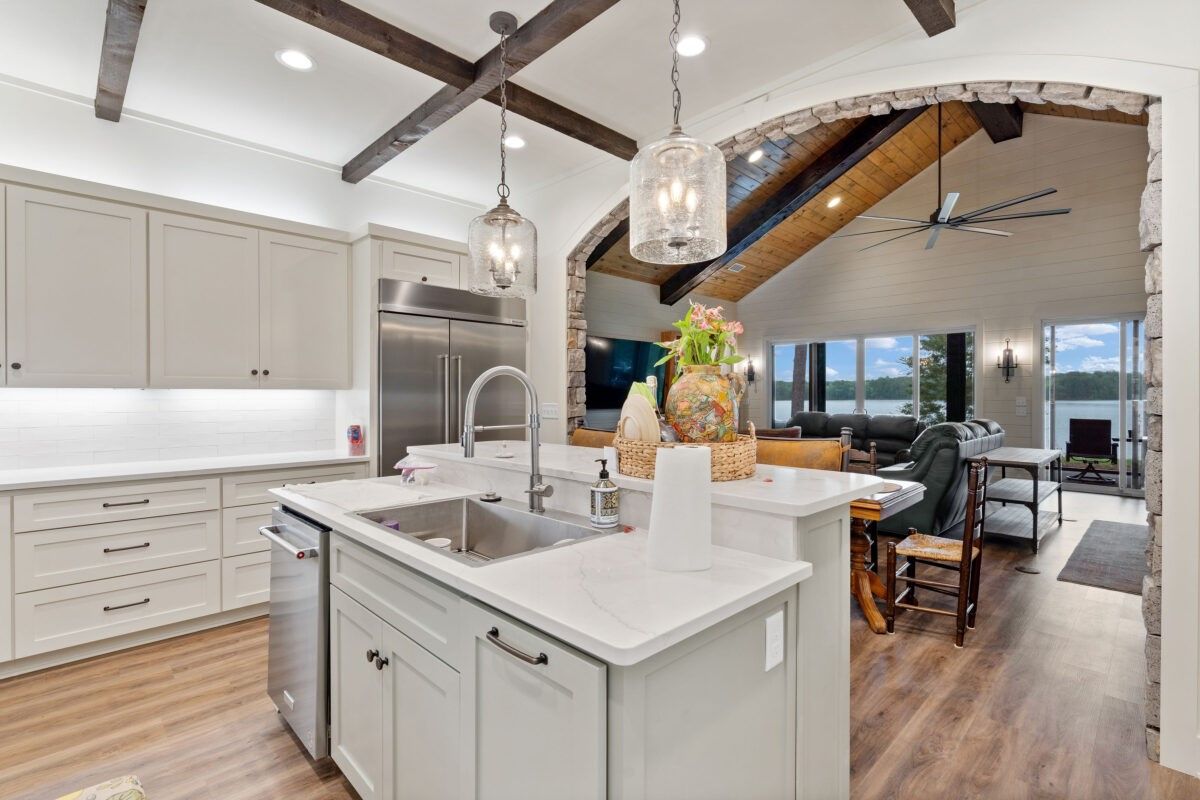 Bright modern kitchen with marble island, pendant lights, and open view to a living room