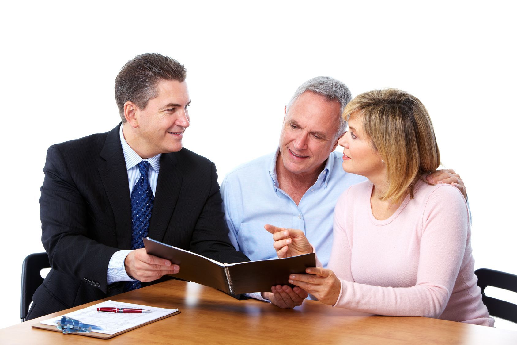Three coworkers in business attire discuss documents around a table, smiling in an office setting.