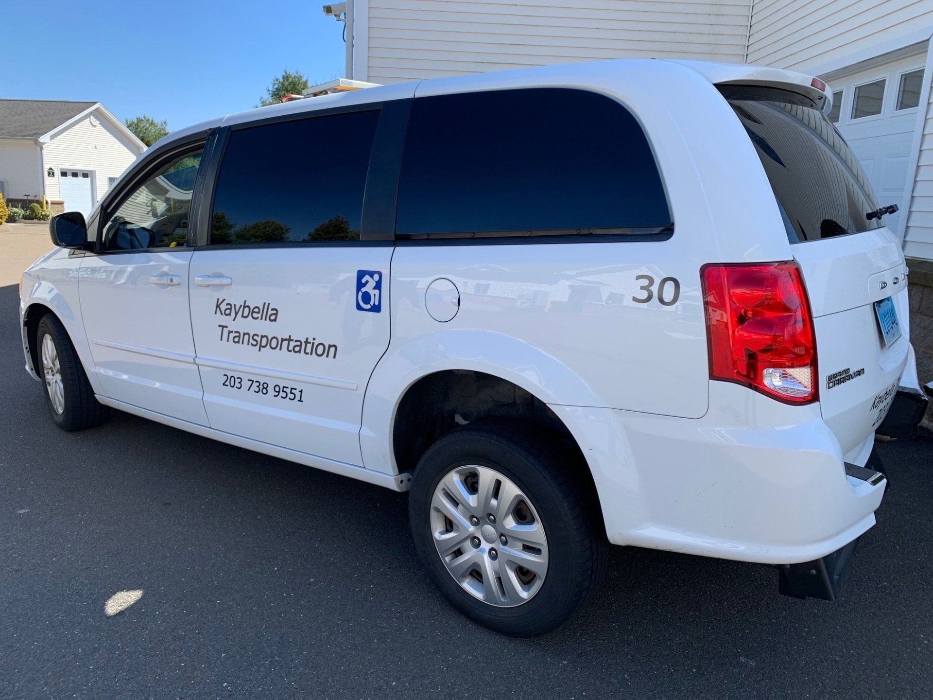 White company van parked in a driveway, with dark tinted windows and logo text on the side.