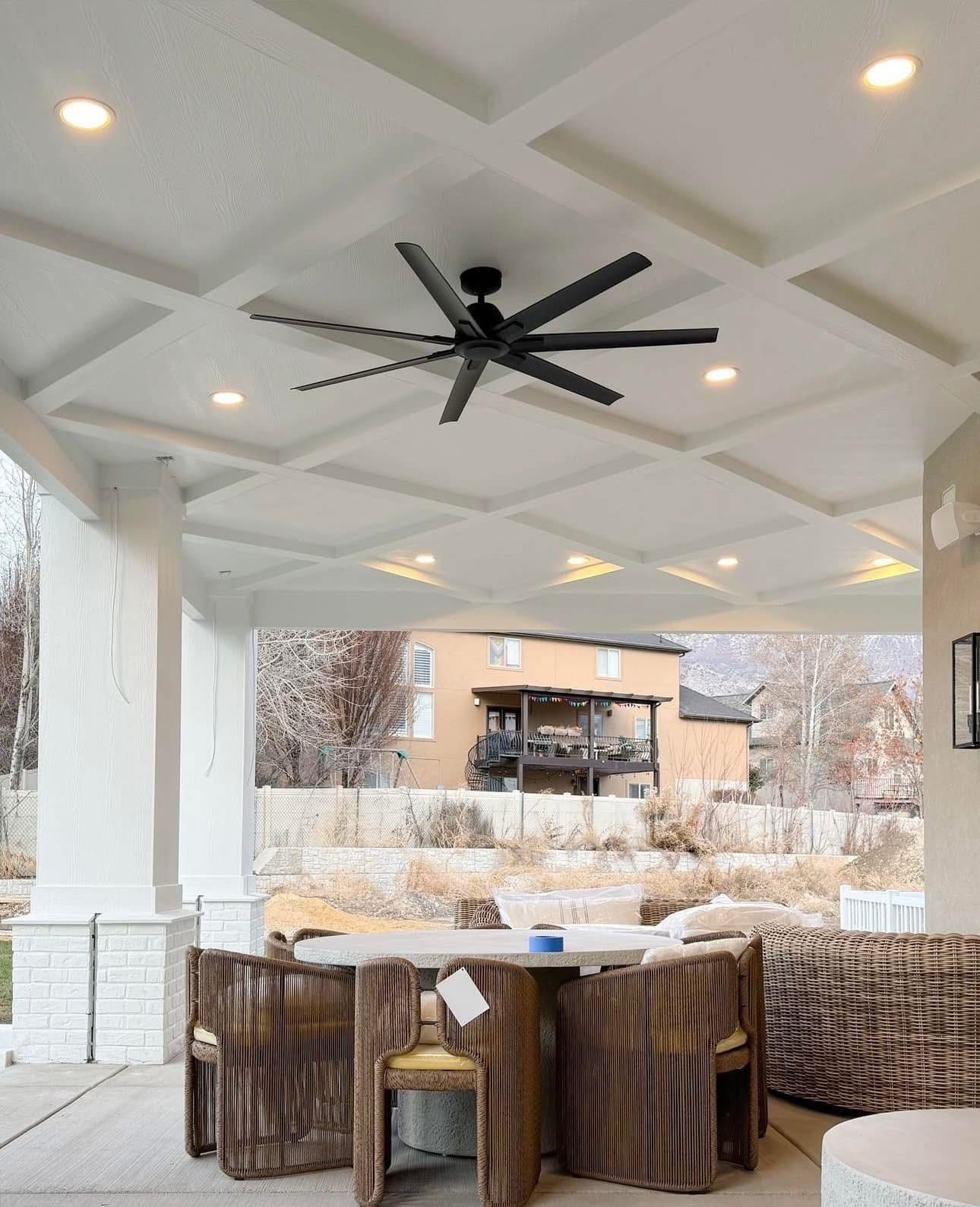 A ceiling fan is hanging from the ceiling of a patio with a table and chairs.