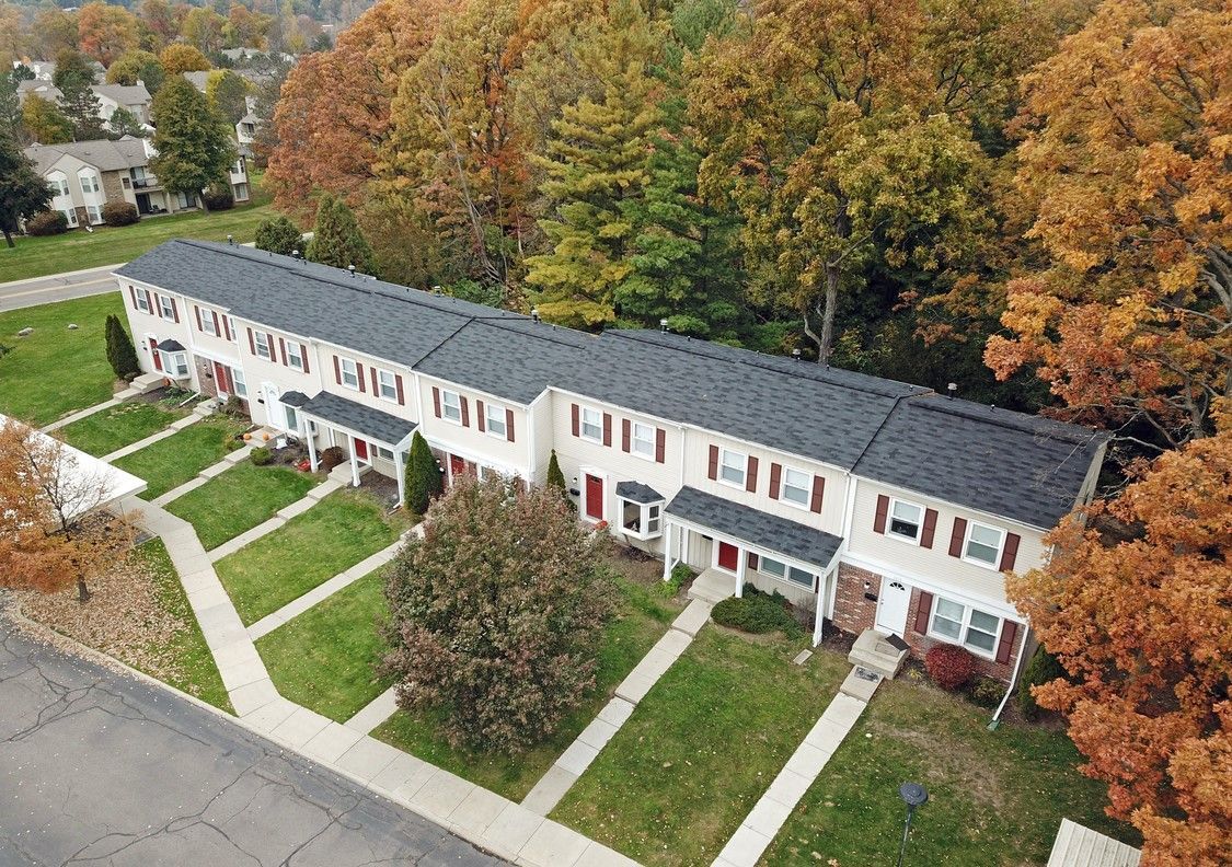 An aerial view of a row of houses with trees in the background.