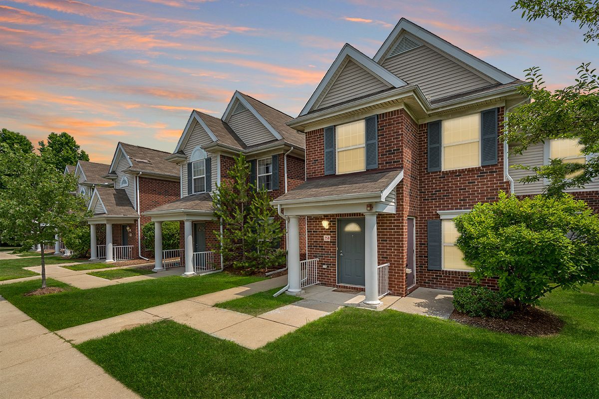 A row of brick houses sitting next to each other on a lush green lawn.