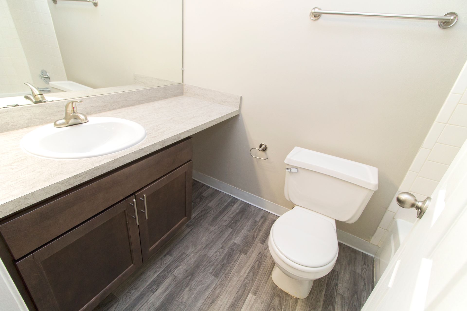 A bathroom with a toilet , sink and mirror.