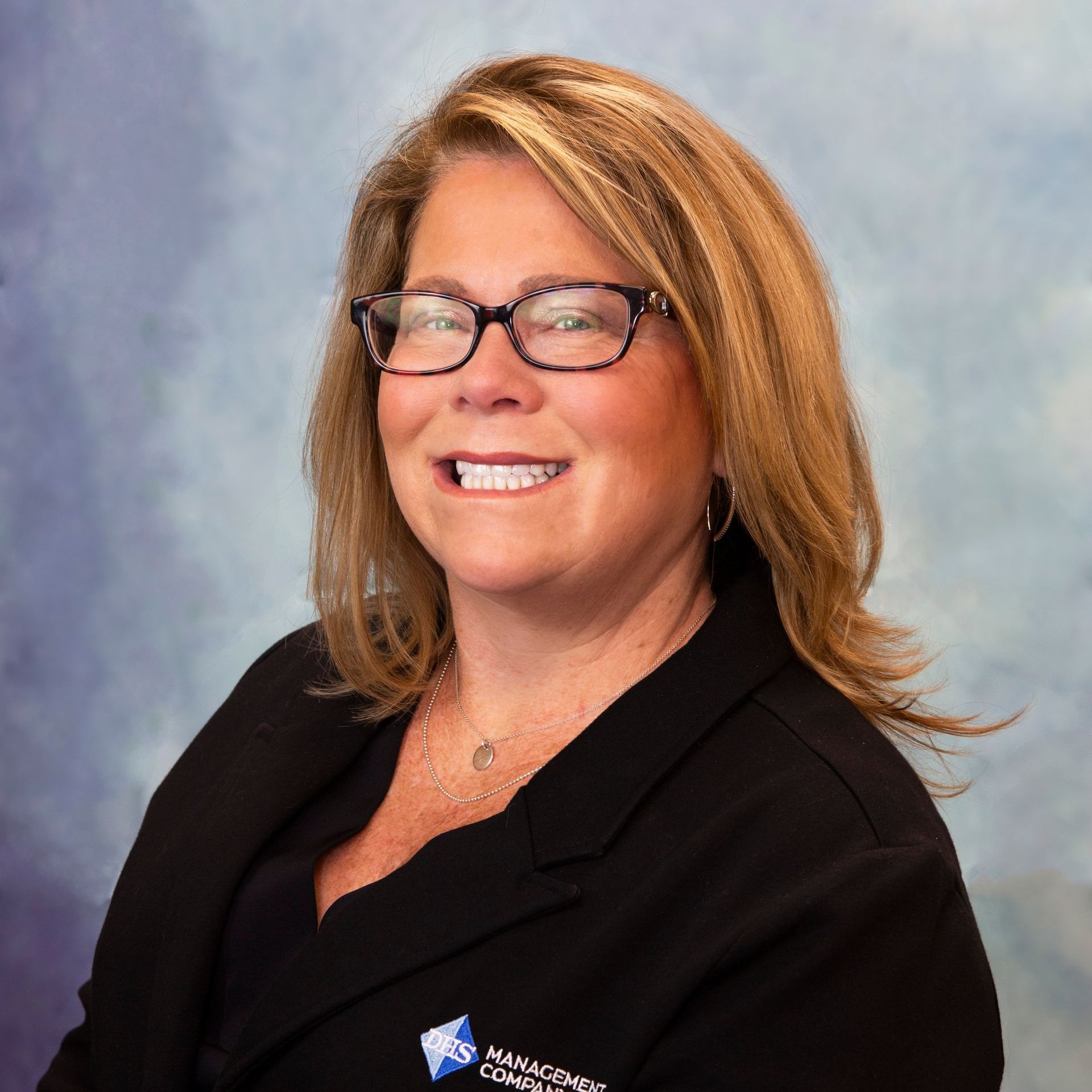 KELLY JANKOWSKI in a blue shirt and black jacket is smiling for the camera.