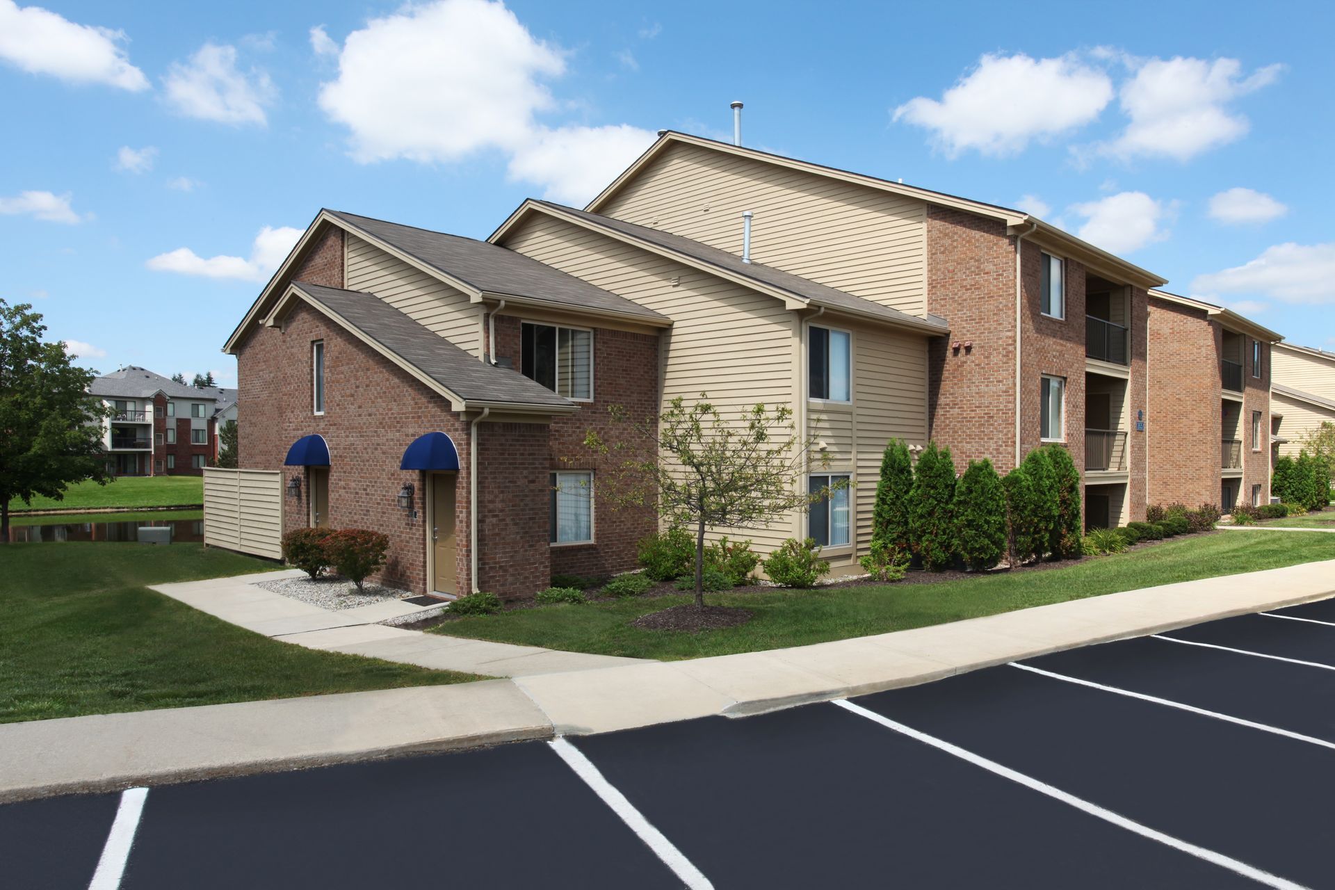 A brick apartment building with a parking lot in front of it