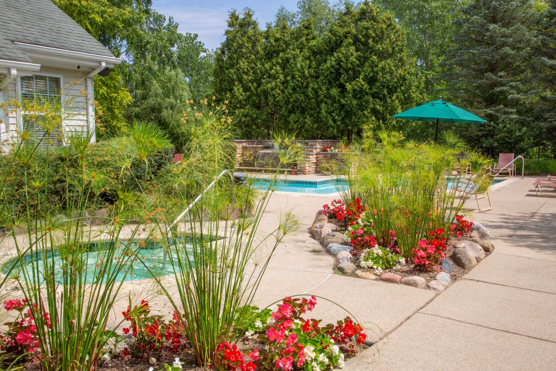 There is a swimming pool in the backyard with a green umbrella.