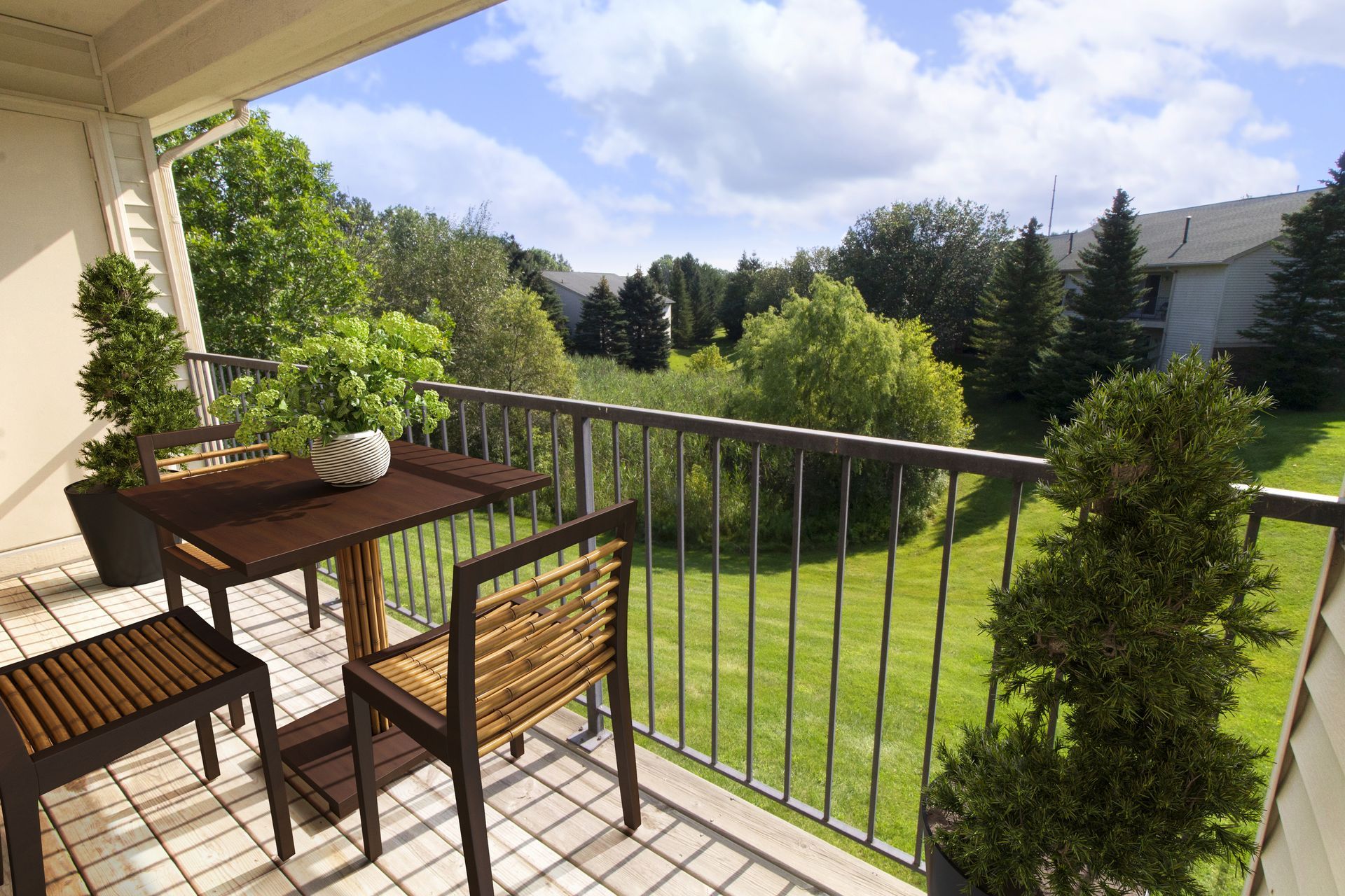 A balcony with a table and chairs overlooking a lush green field.