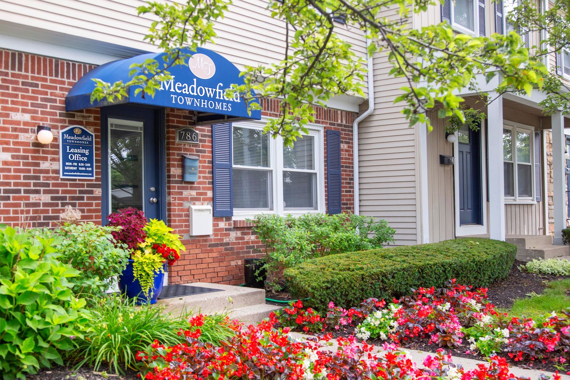 A brick building with a blue awning and flowers in front of it.