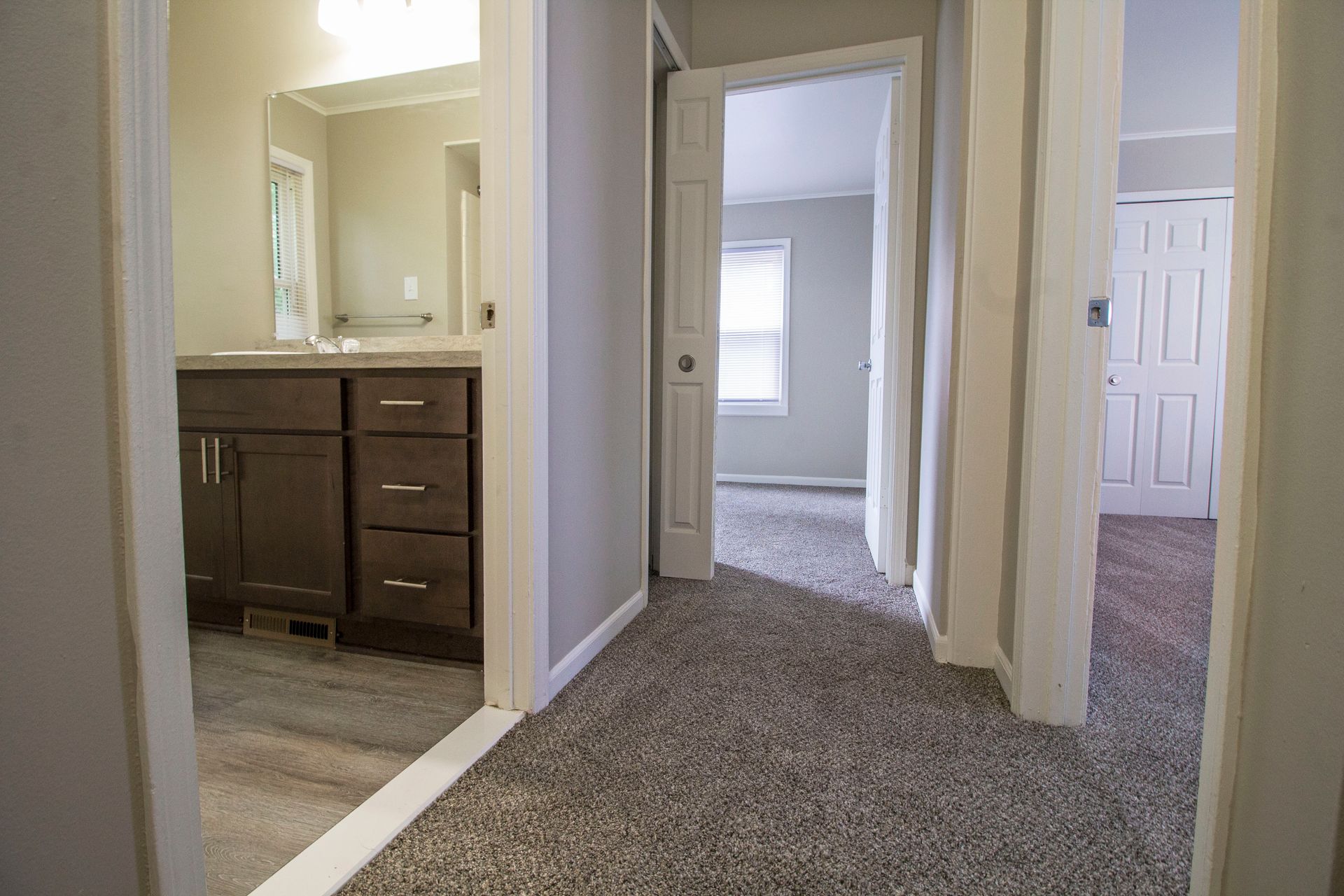A hallway leading to a bathroom and a bedroom in a house.