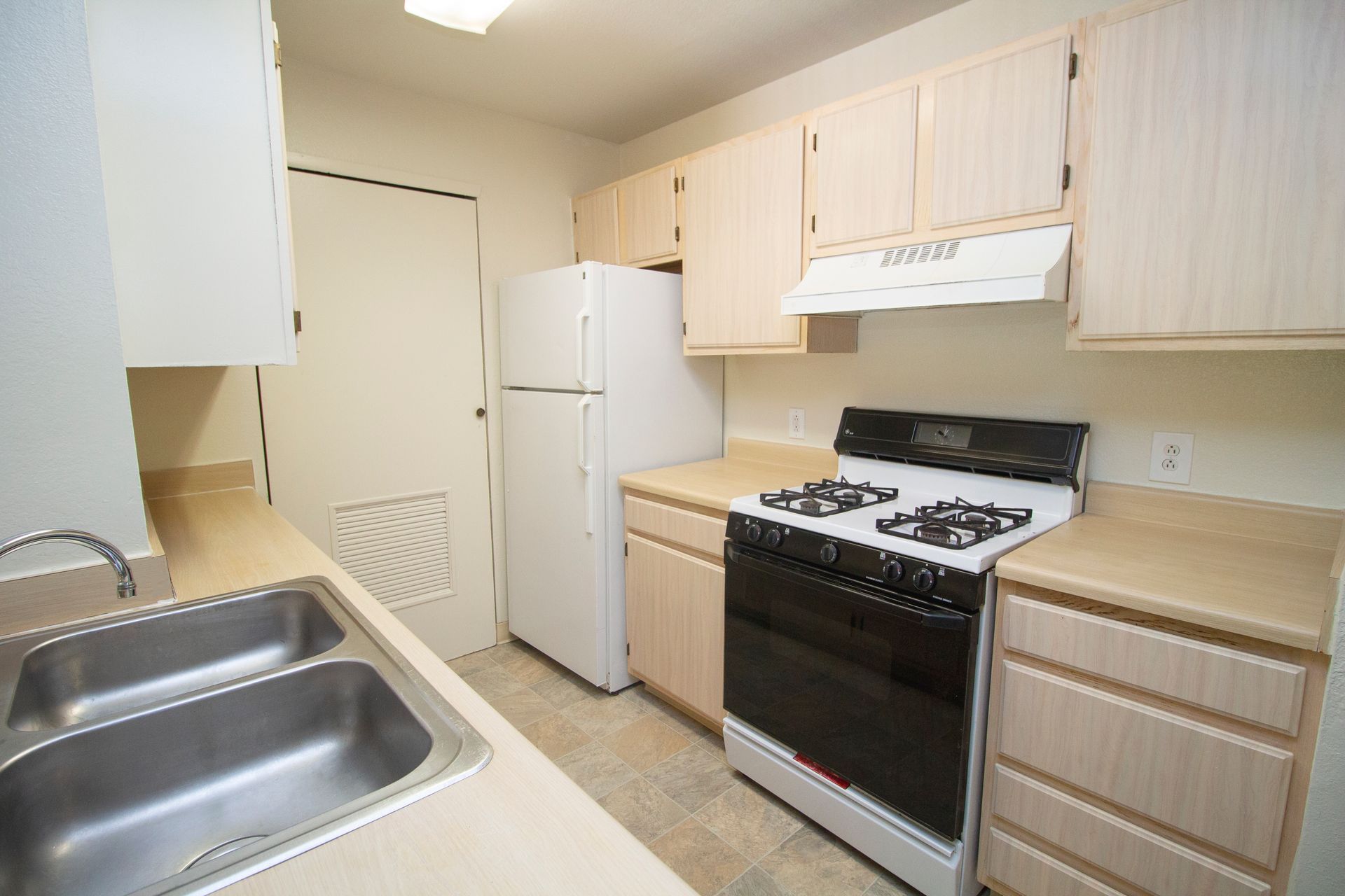 A kitchen with a stove , refrigerator and sink