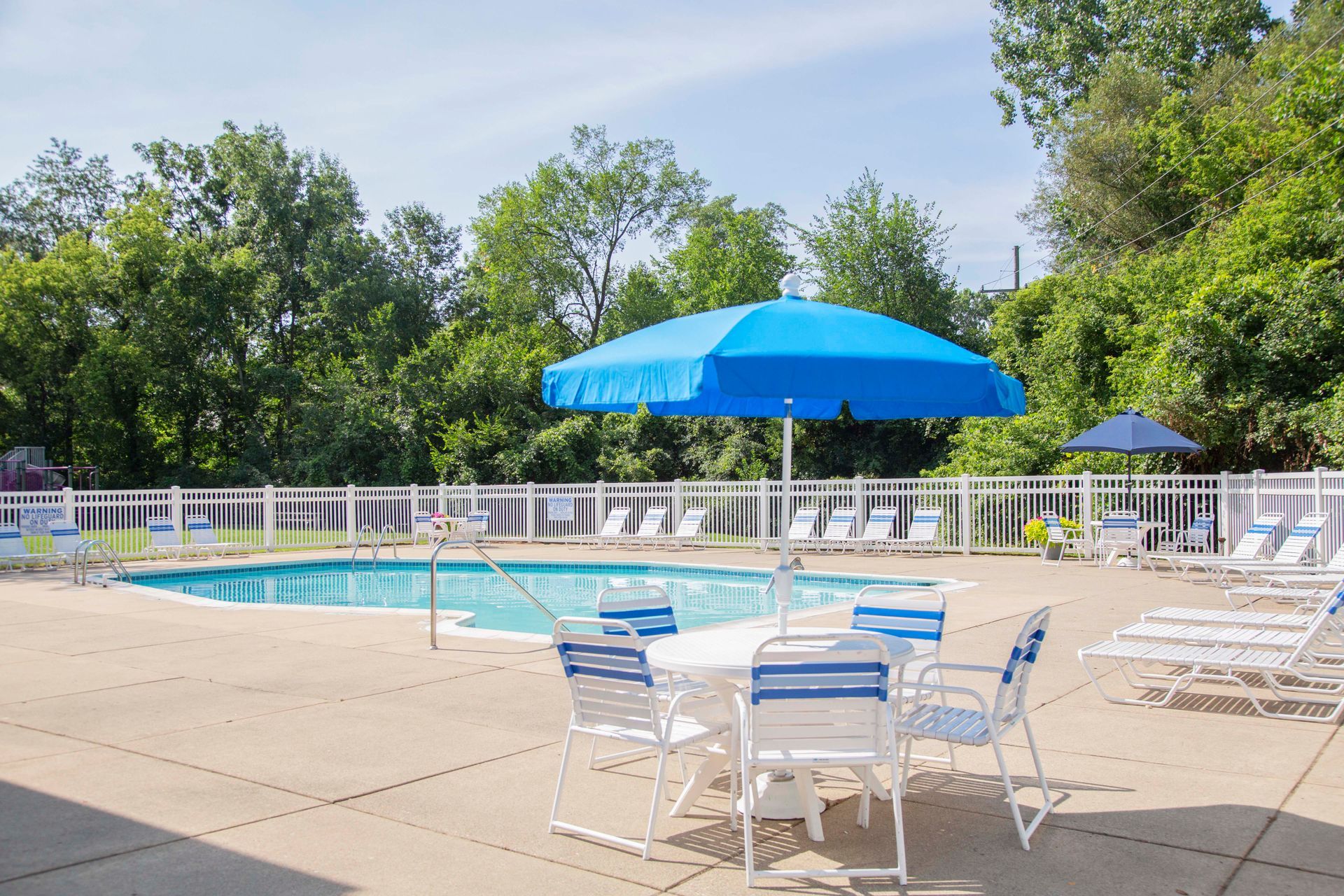 A swimming pool with a table and chairs under an umbrella