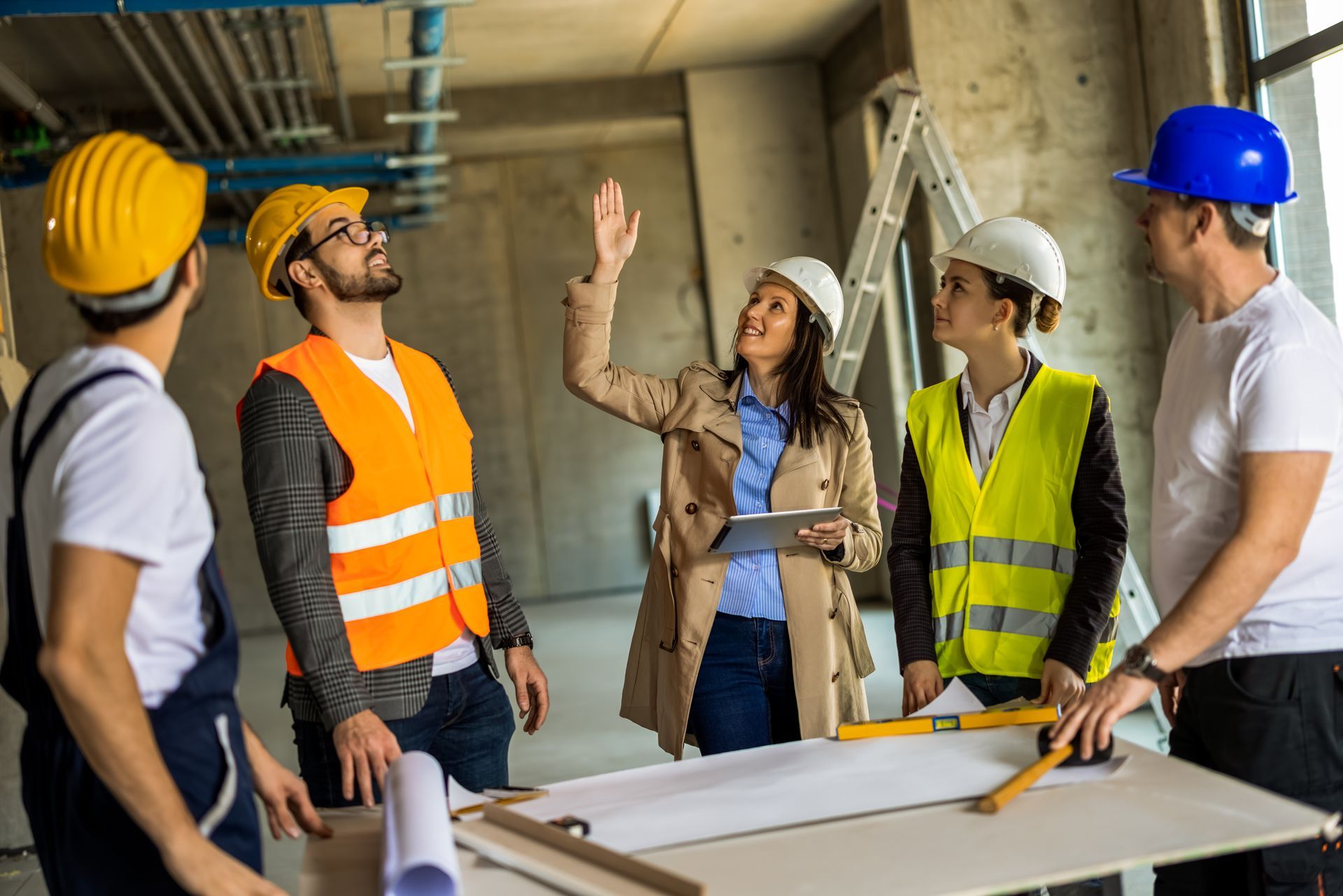 Construction team discussing blueprints at a building site, with hard hats and safety vests.