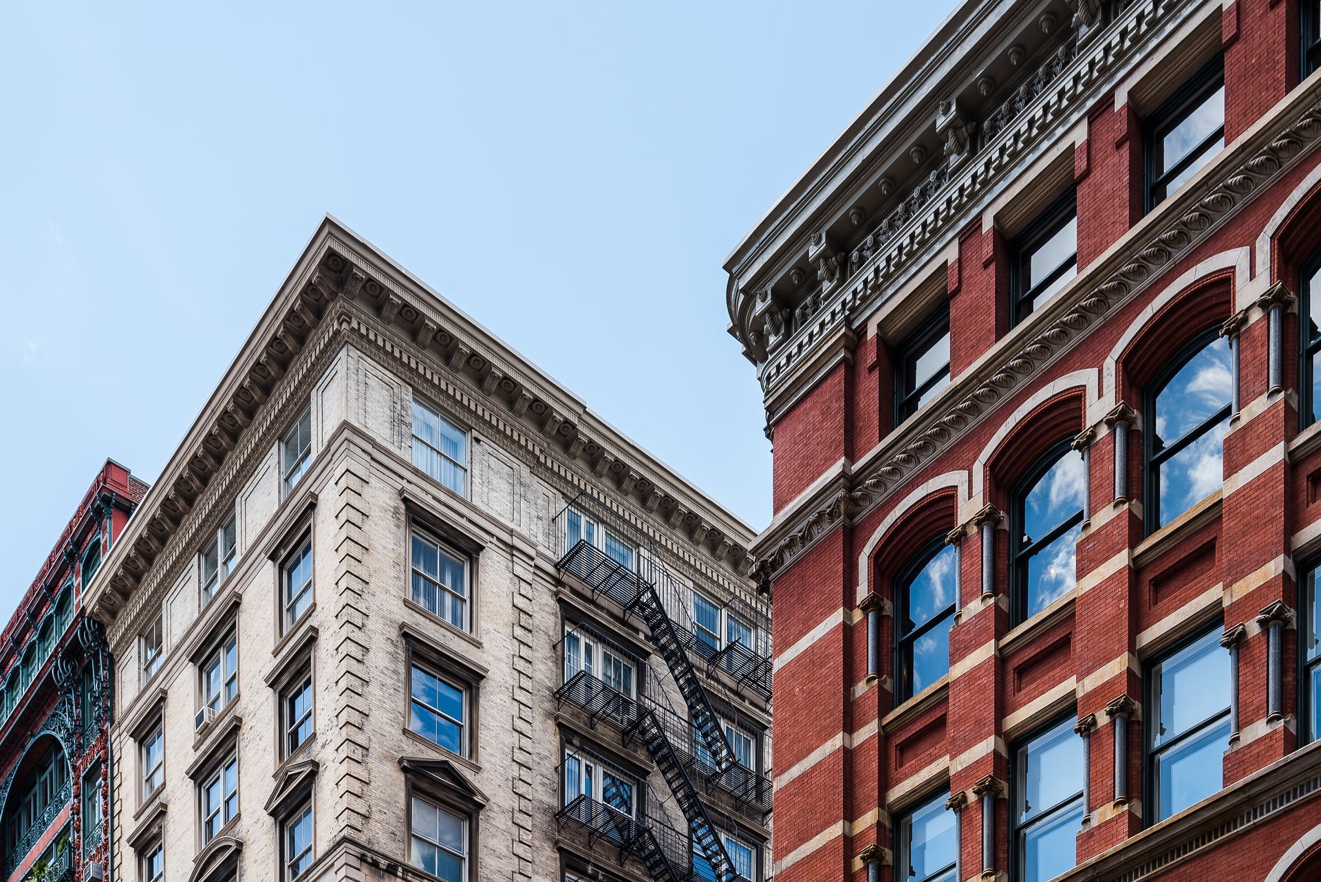 Tall red and beige city buildings with ornate facades against a blue sky