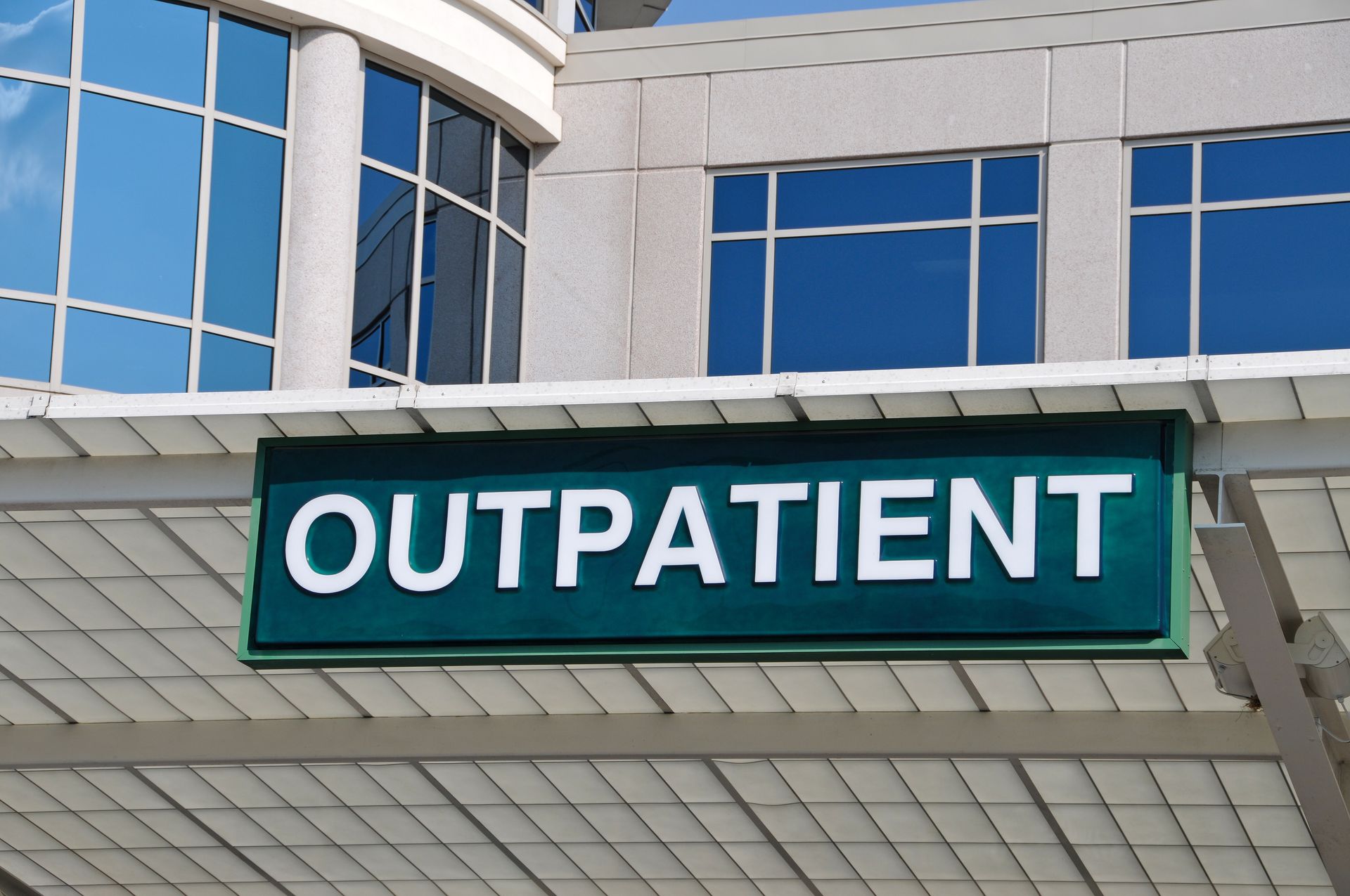Green outpatient sign on a modern hospital building.