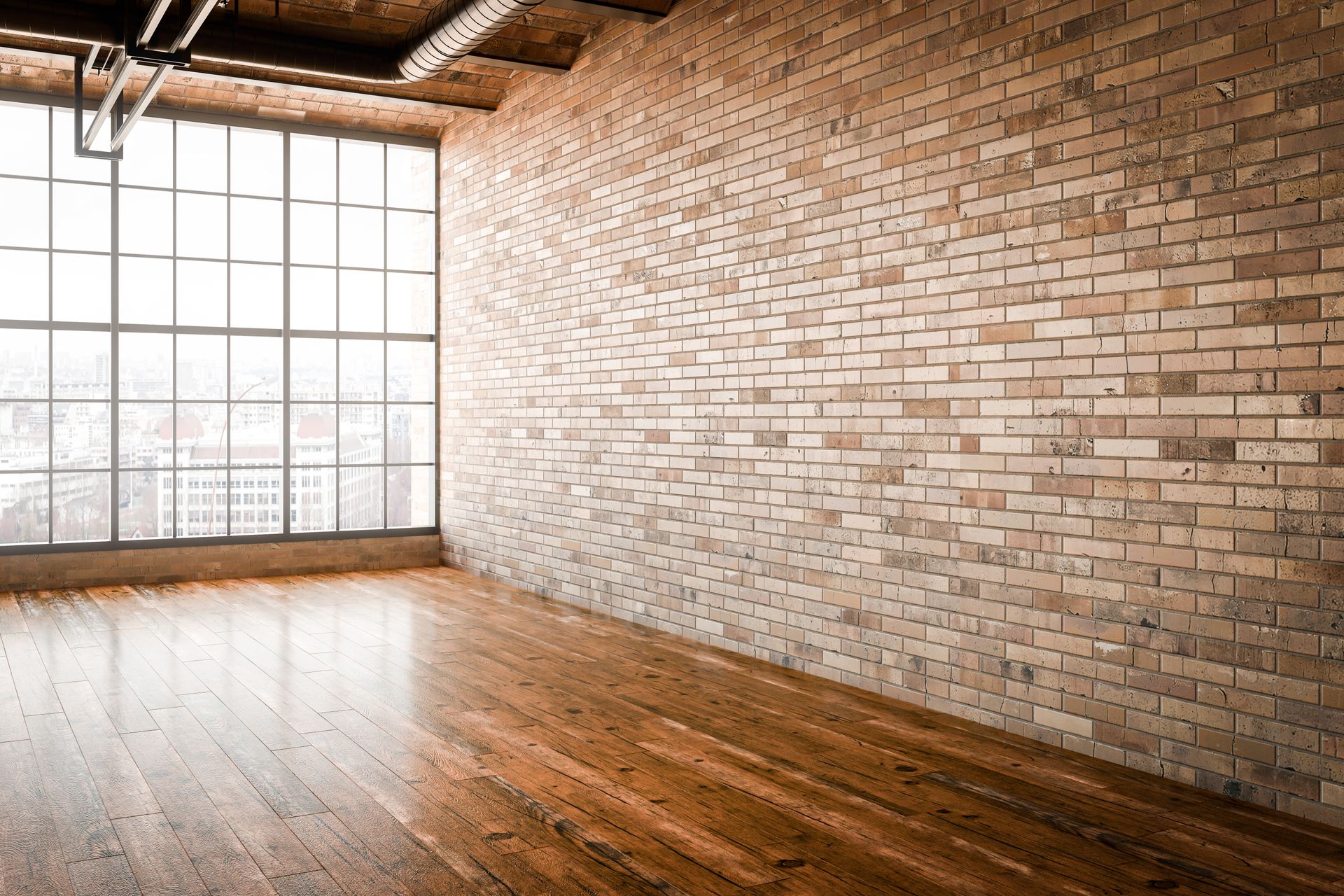 Empty loft with exposed brick walls, wooden floor, and large industrial windows.